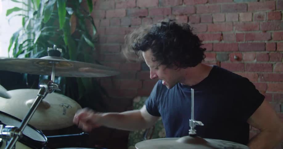 A young white man plays a drum kit
