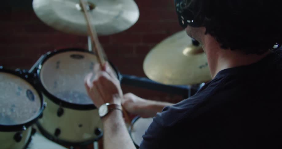 A man plays drums with headphones on