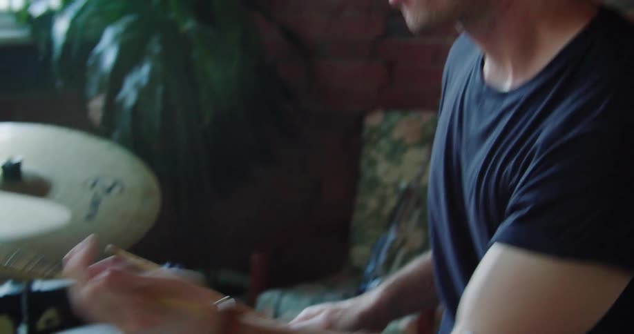 A drummer using a drum set indoors