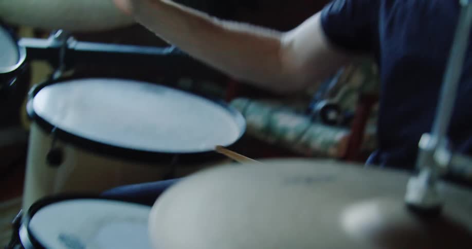 A man drumming on a drum set indoors