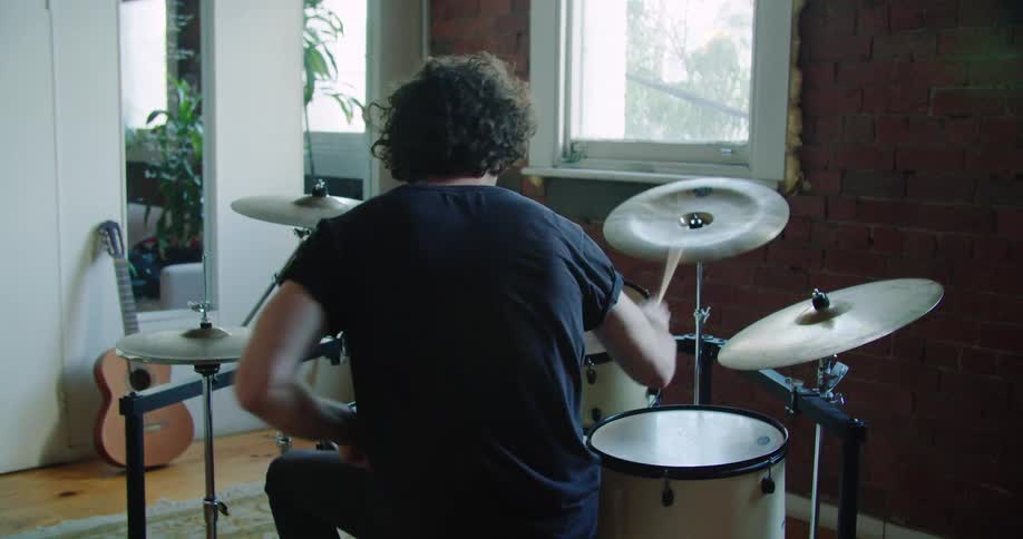 A man practices the drums in a studio