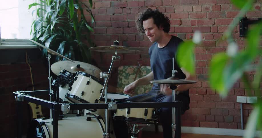 A man is playing the drums in the corner