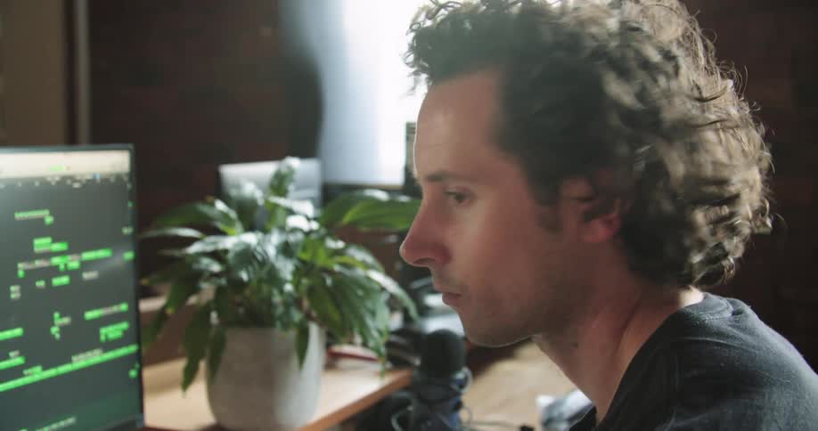 A young man nods his head as he sits in front of a computer screen