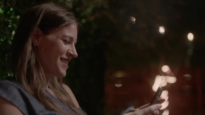 The woman sitting outside touching her smart phone