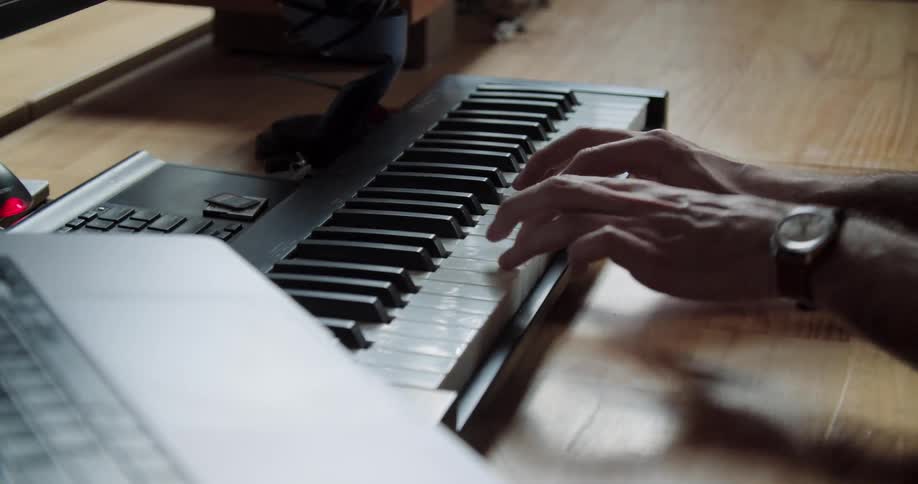 A musician plays a musical keyboard connected to a computer
