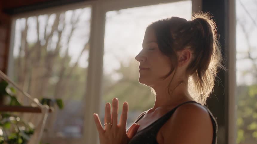 A woman standing inside meditating