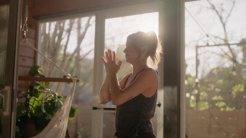A woman is doing yoga on her porch