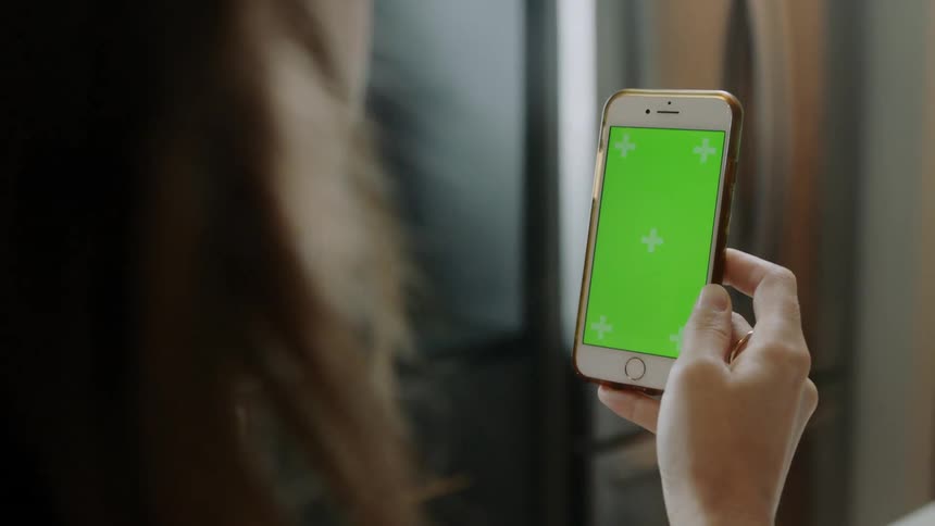 A woman nods her head while looking at her phone screen