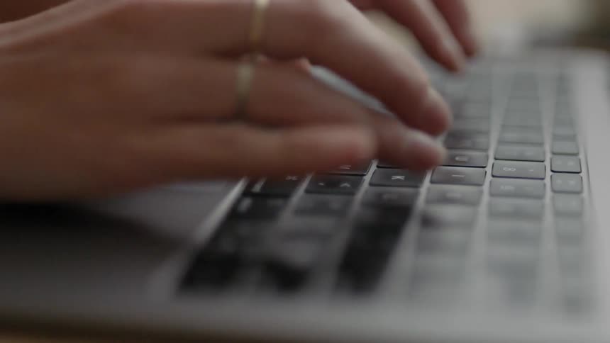 Woman sitting at the desk types on laptop indoors