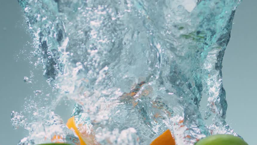 Citrus halves plunge through water leaving bubbles and ripples