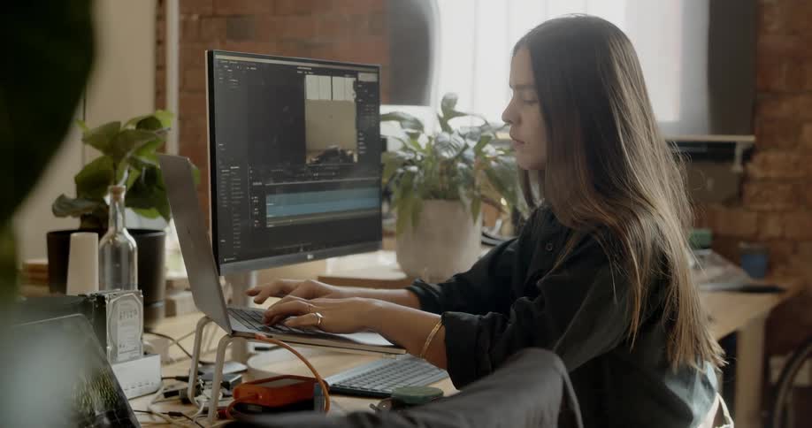 A woman sitting at a workstation typing on a laptop