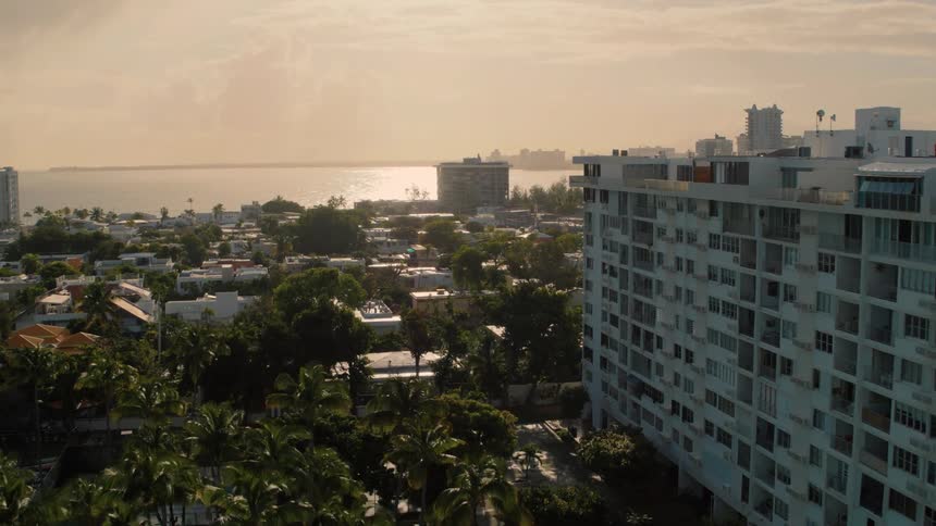 The sunlight reflects off the ocean water rooftops and swimming pools of a coastal city