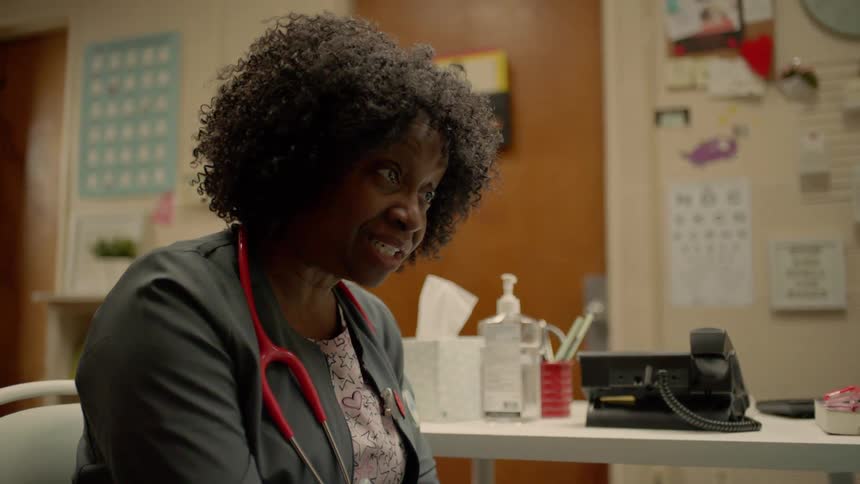Black female doctor sitting on a chair talks to a patient in the clinic