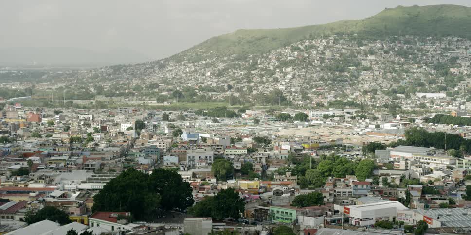 A city spread out at the base of a hill with homes built up on the hill slope