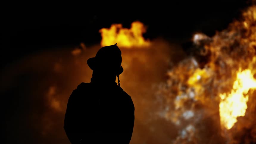 Firefighter silhouetted by smoke and fire