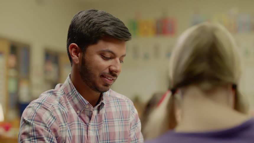 A teacher in a classroom talking to a student