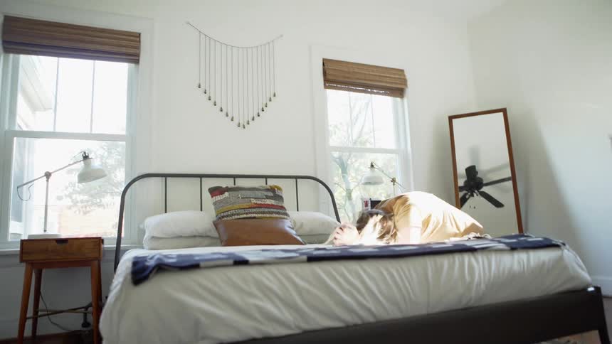 A white woman gets up from a bed and performs several stretching movements