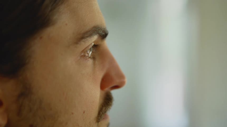 Man blinks his eye as he looks straight ahead