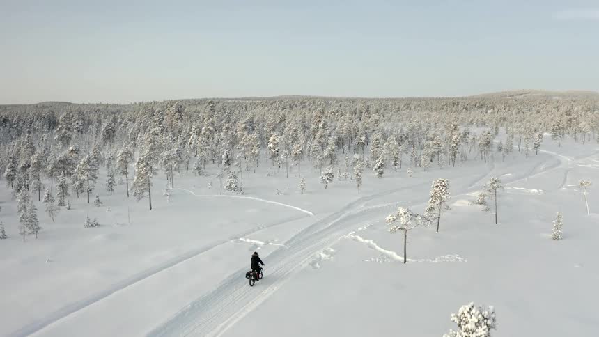 Man rides a bicycle on snowy forest road track
