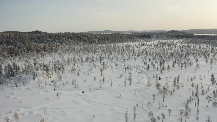 Traveling aerial shot of riding a bike through snowy wilderness
