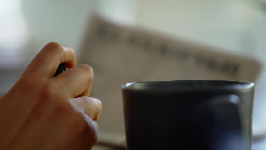 A person fidgets with a marker while reading a newspaper classified section