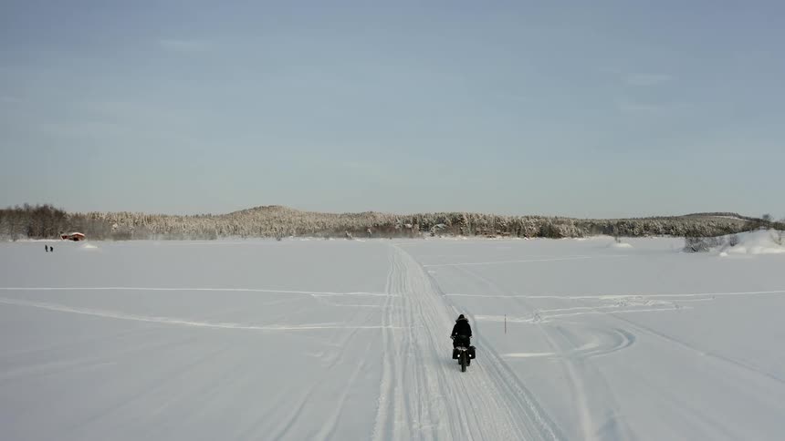 A person rides their fatbike over the snow covered field