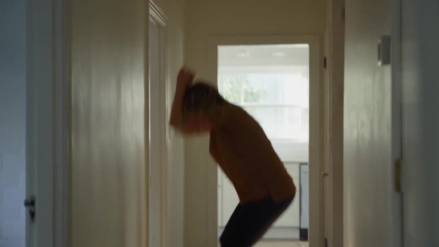Blonde woman dancing in hallway of her home while quarantined