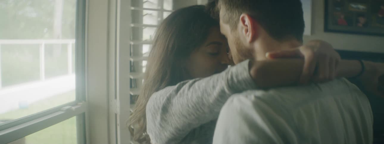 Two people hug near the window