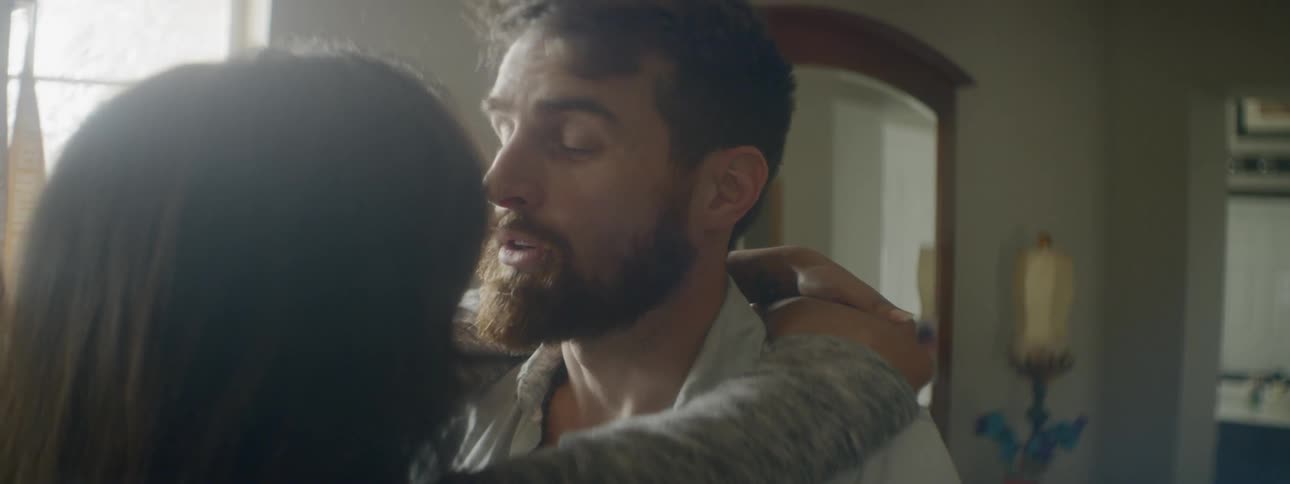 A man and a woman embrace inside a house