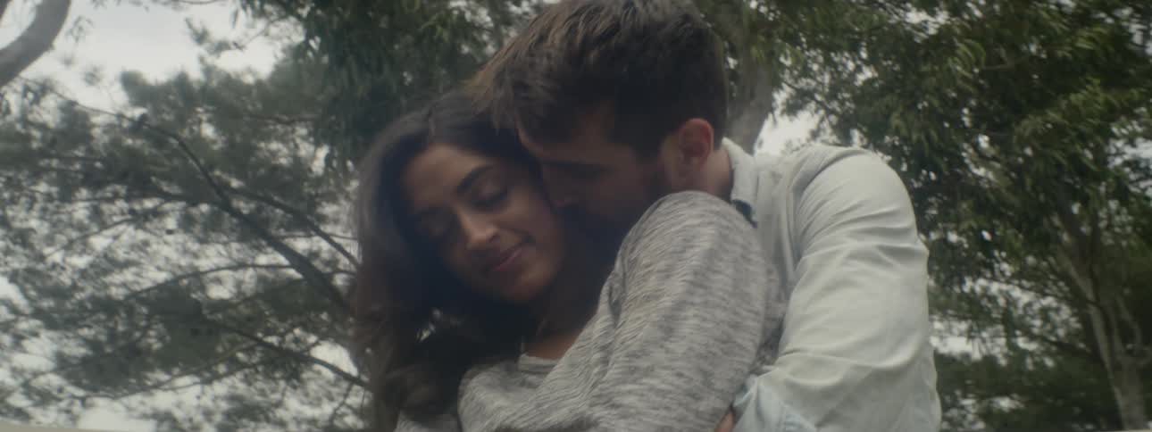A man and woman hug and kiss outside