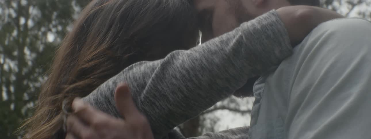A man and woman hugging each other close outdoors