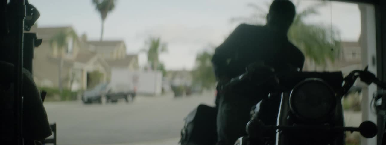 A man grabs his helmet and gets on his motorcycle