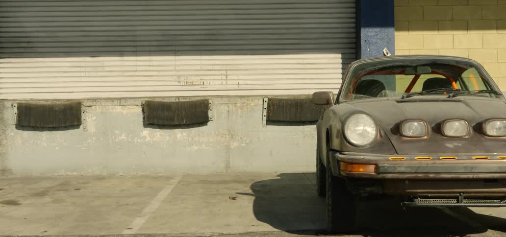 A dirty car sits in a parking spot