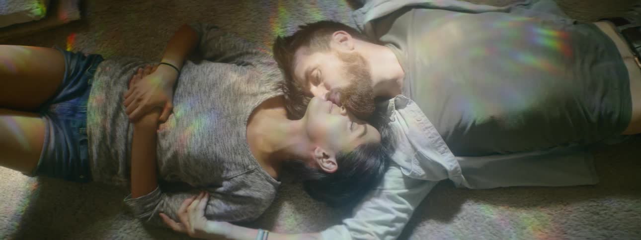 Man and woman lie down on the carpet and kiss each other in the living room