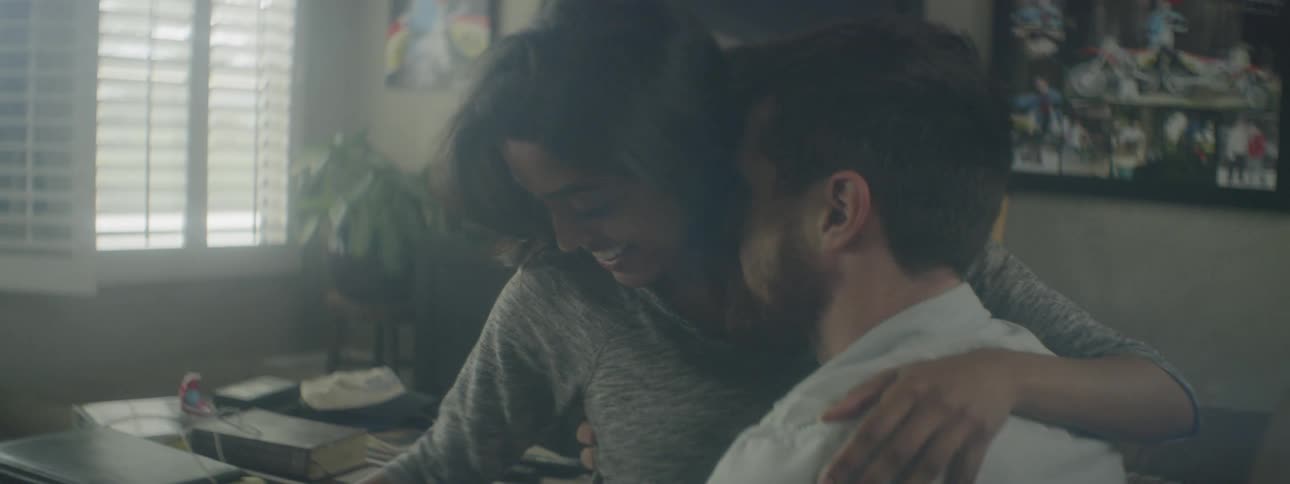 Woman sitting on mans lap pets grey dog in the living room