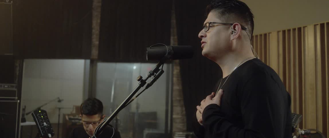 A man singing into a microphone in a studio