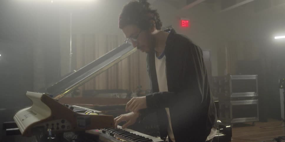 A man is bobbing his head to music while he plays an electric keyboard