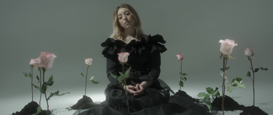 A woman sits between flowers