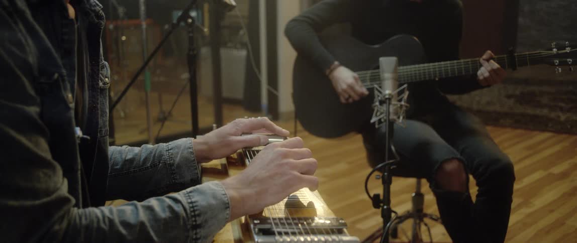 Two musicians playing instruments in a recording studio