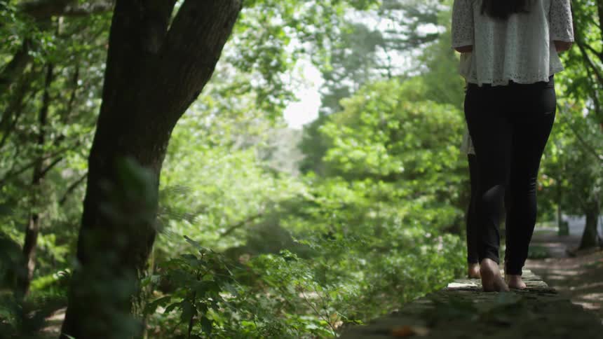 Two women walk down a path barefoot