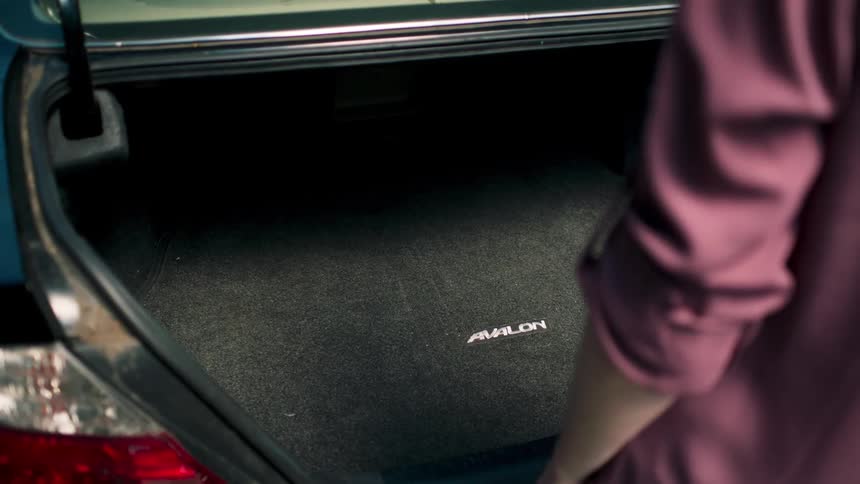 A woman stands in front of her open vehicle trunk