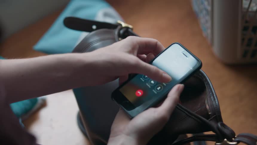 A woman pressing the speaker button on her phone