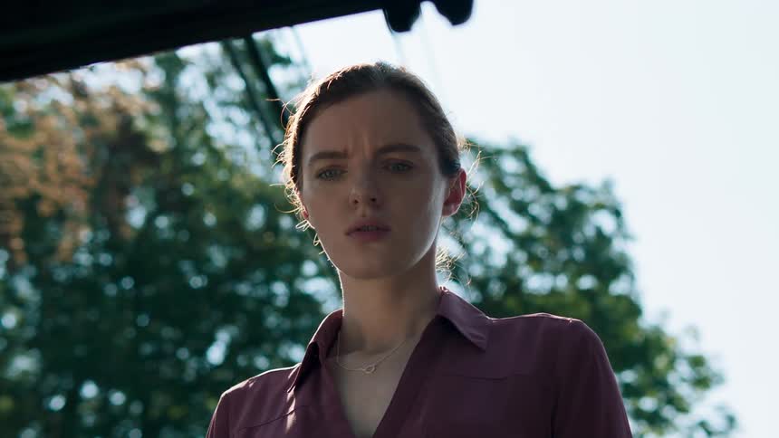 A woman standing outdoors with a puzzled expression on her face