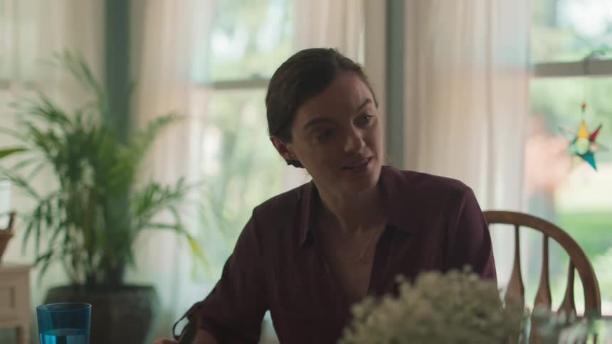 A woman talking while sitting at a dinner table holding a knife