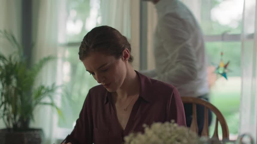 A man kisses his wifes forehead as she eats dinner