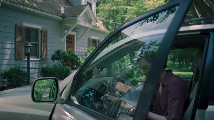 A young woman gets into her vehicle outside of a house