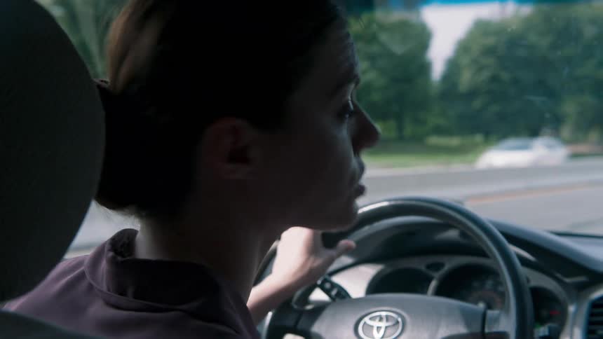 A woman looks behind her while driving a car