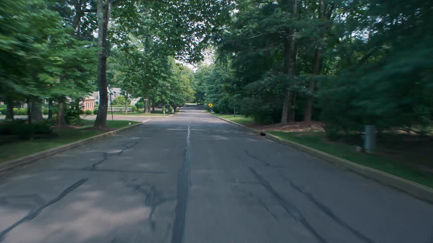 A vehicle travels down a rural neighborhood road
