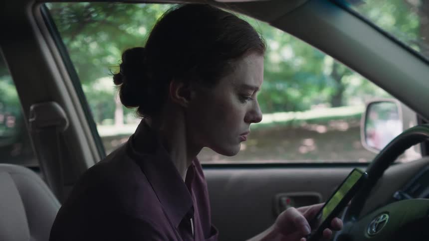 A woman uses her phone while sitting in her car