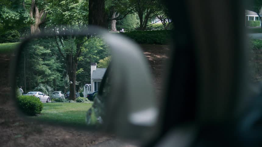 Looking through a cars side mirror at a person in a driveway